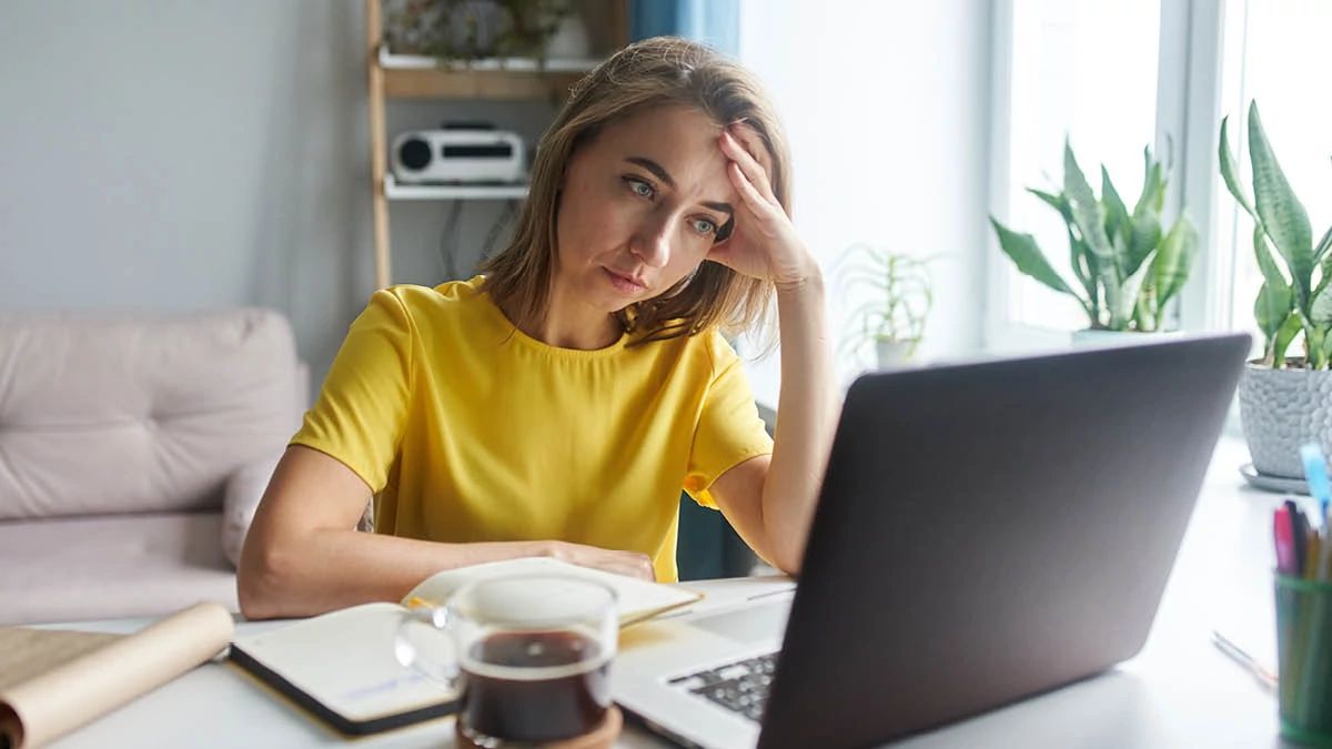 Woman sitting at her desk in front of laptop computer looking fed up