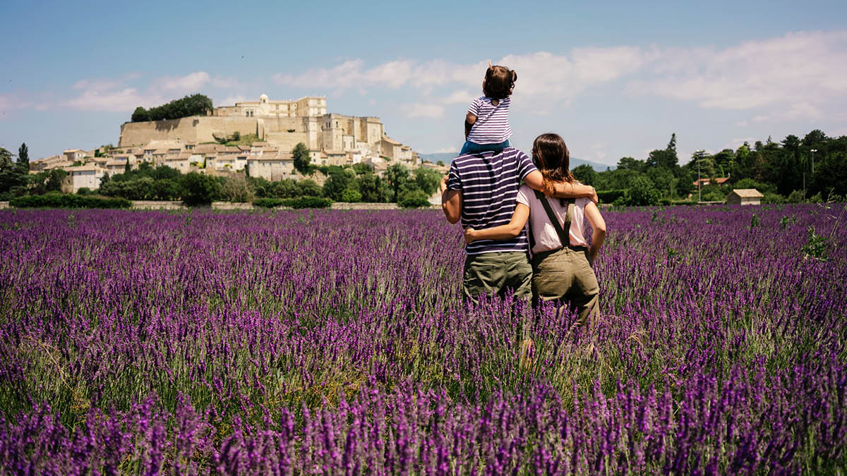 A family standing in a French lavender field looking at a beautiful view of old buildings